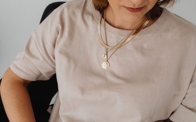 Une femme porte un t-shirt beige et un collier doré