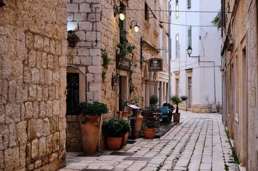 Une ruelle étroite aux murs de pierre, pots et lampes